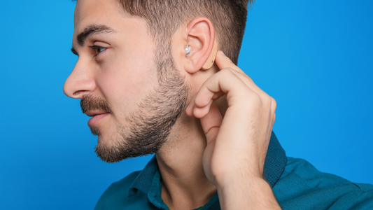 Person adjusting the volume on their hearing aid with a focused expression.