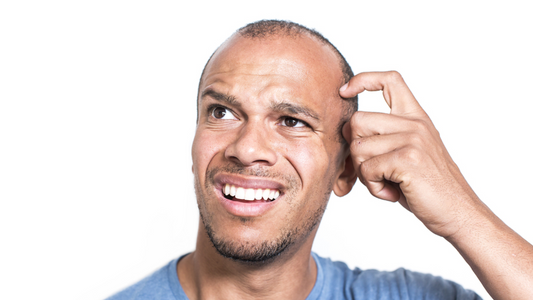 Image of a person sitting in a quiet room, looking puzzled and holding their ear as if listening to a low hum.