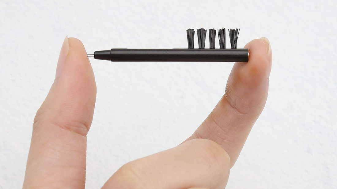 Image showing various tools for cleaning hearing aids - soft toothbrush, microfiber cloth, and a wax pick or loop tool, arranged neatly on a table.