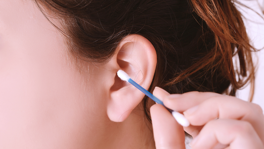 Illustration of a person gently cleaning their ear with a cotton swab.