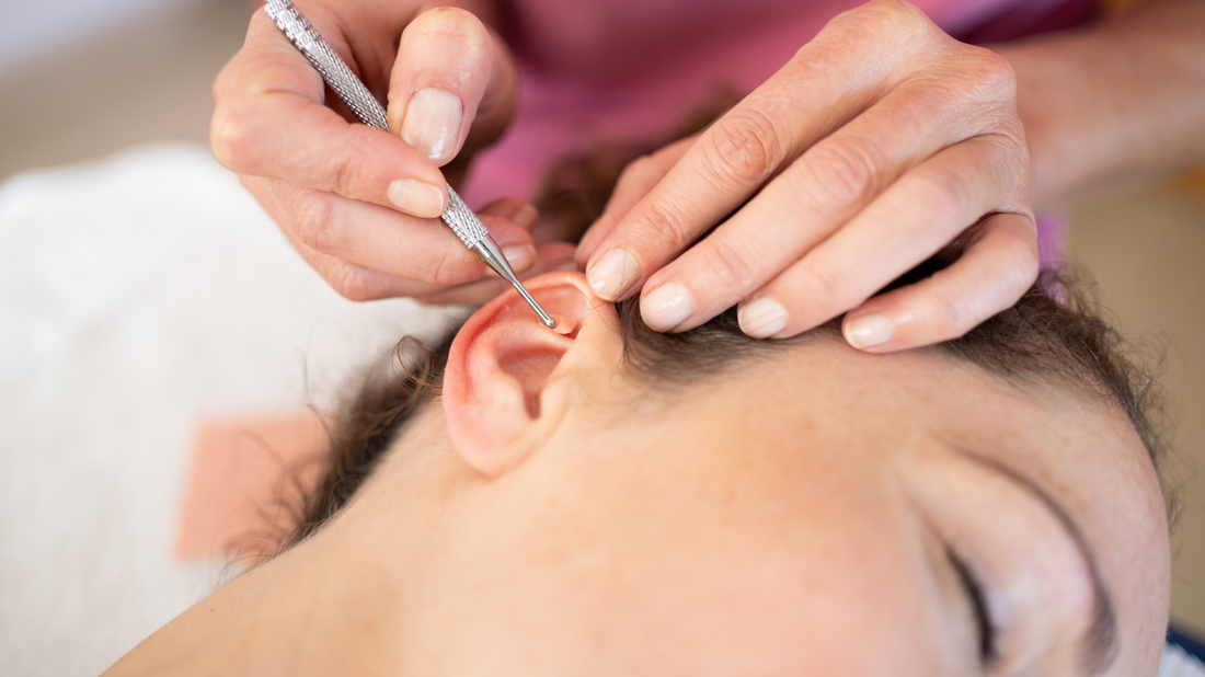 An image depicting a professional performing an ear cleaning procedure on a patient. The professional is using a specialized tool to gently remove earwax, demonstrating a safe and careful process.