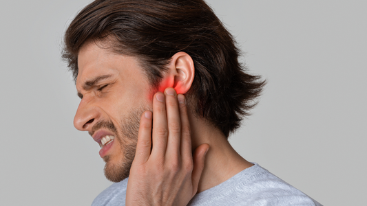 An image depicting a person holding their ear in pain, indicating symptoms of ear injury such as redness, swelling, and discomfort