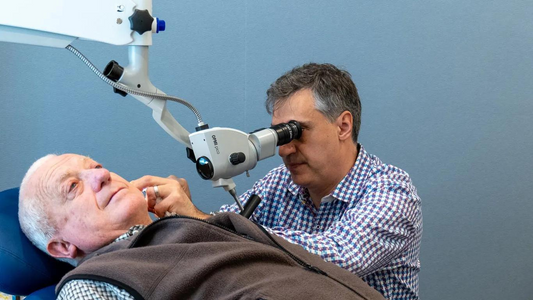 Illustration of a person having ear wax removed by a healthcare professional, showing the process of ear wax removal.