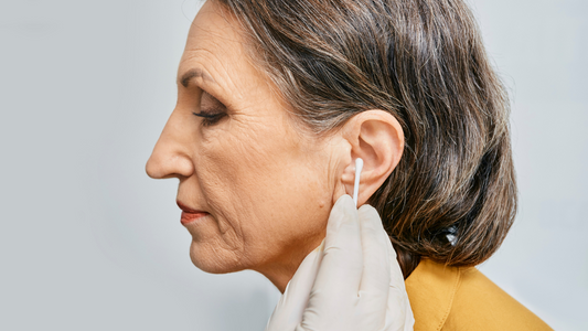 Image showing a close-up of an ear being cleaned with a cotton swab, representing the process of earwax removal. This image illustrates one of the causes of a clogged ear and a common remedy