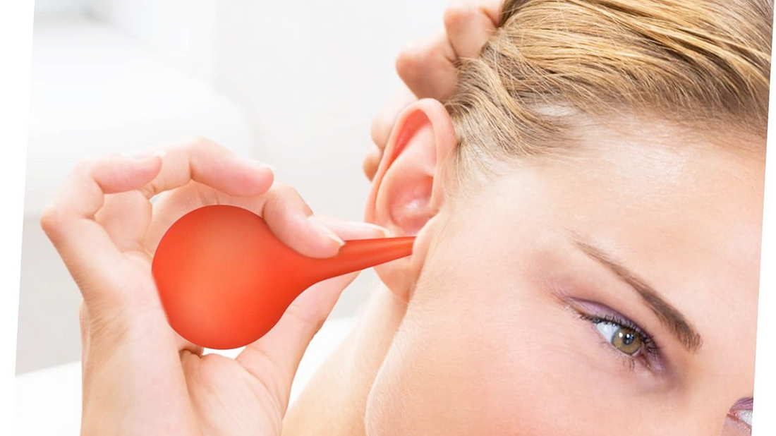 A person tilting their head while using a rubber-bulb syringe to remove earwax.