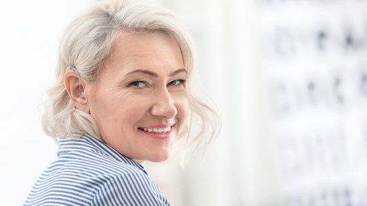 A person smiling while wearing a hearing aid, showcasing satisfaction with their choice.