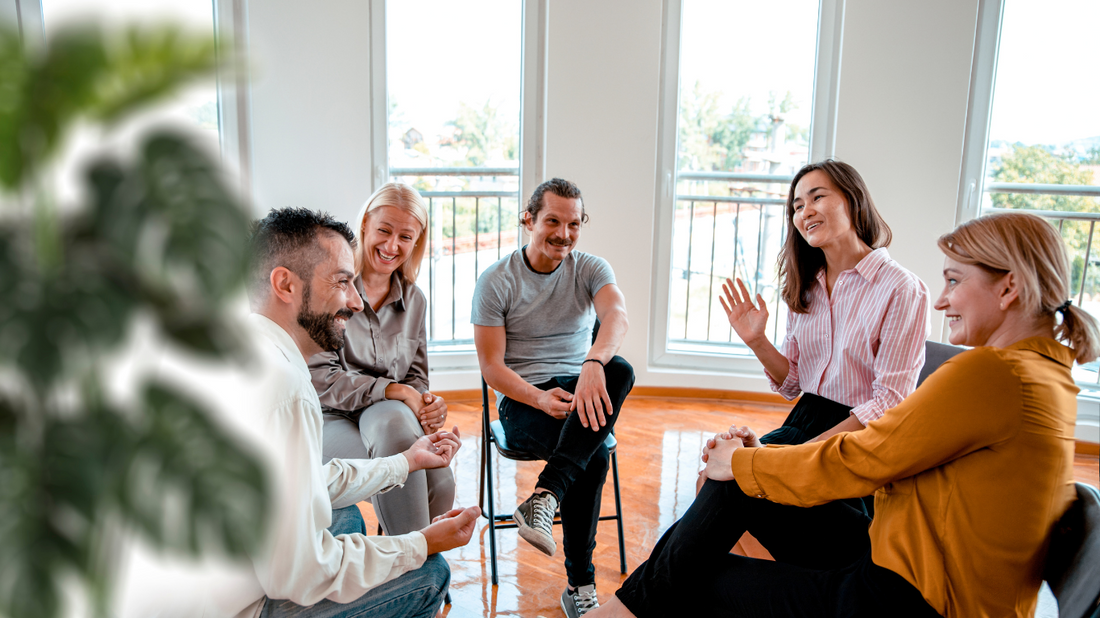 An image of a diverse group of people engaged in conversation, smiling and gesturing comfortably.