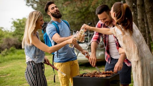 A group of people conversing at a barbecue, one person appears to be wearing a hearing aid.