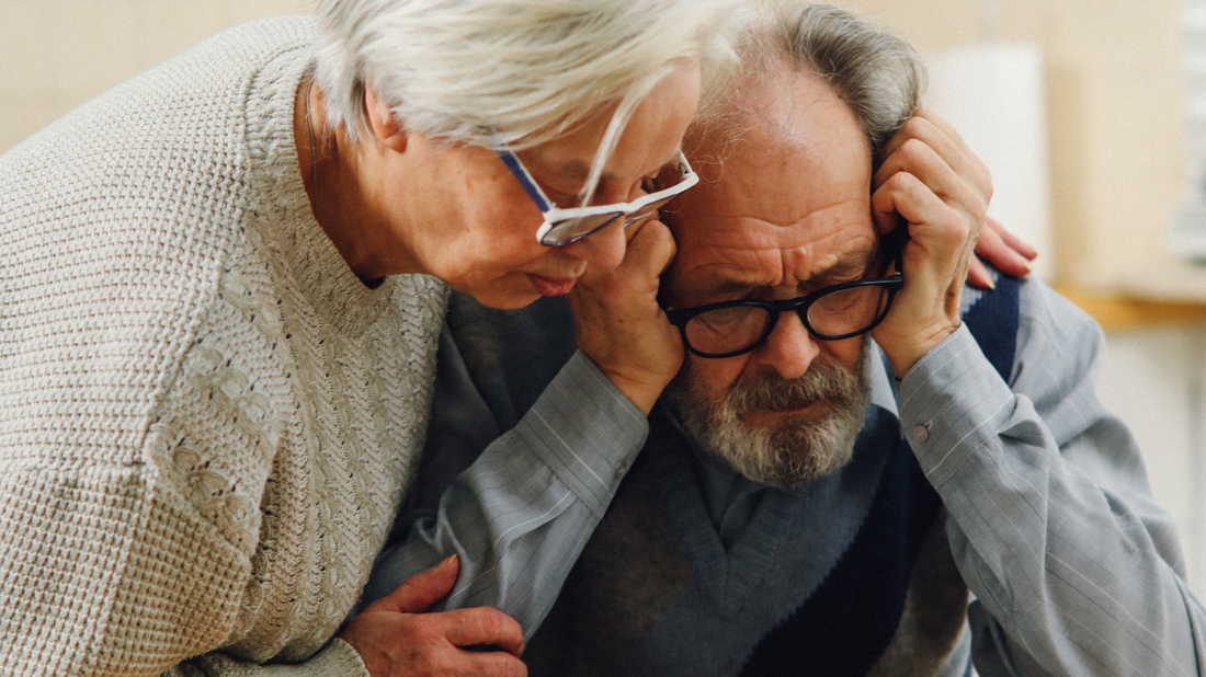 An illustration depicting a couple sitting, but looking concerned about their hearing.