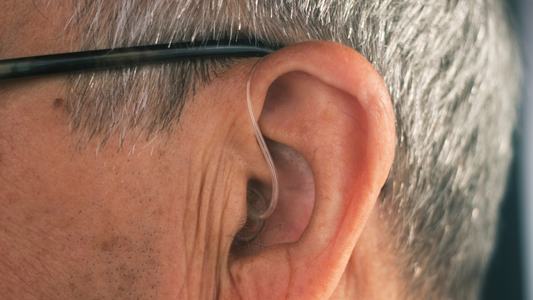 Close-up of a person wearing a discreet HearWell Group hearing aid.