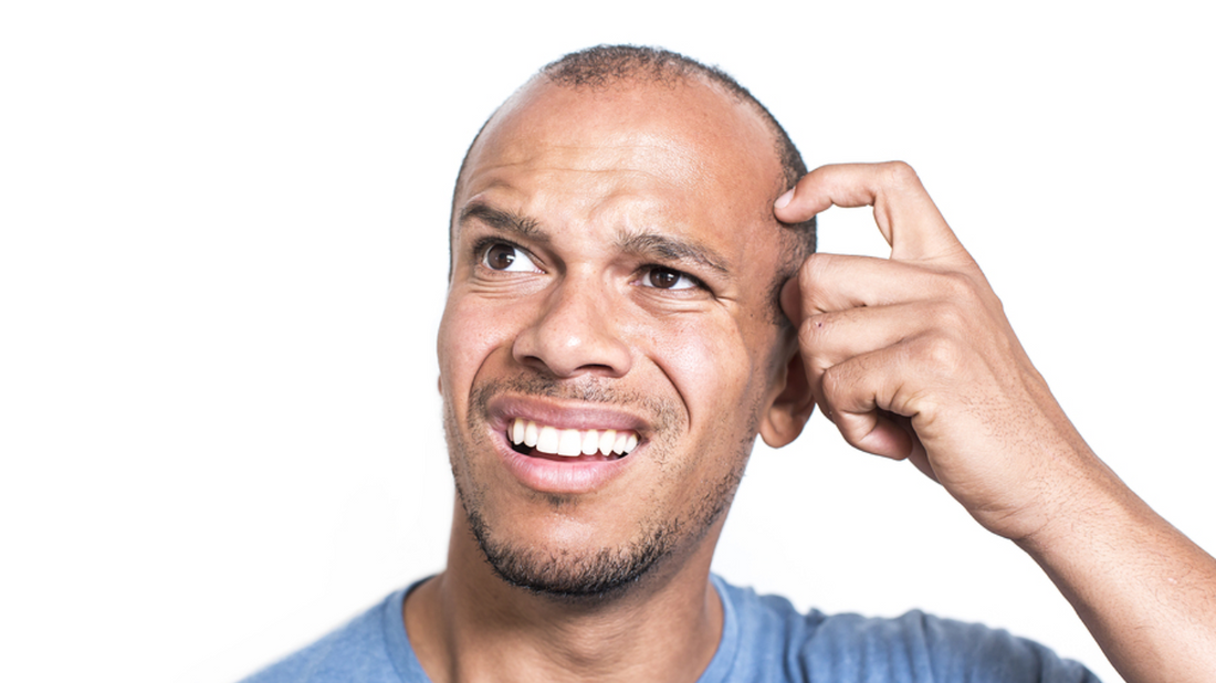 Image of a person sitting in a quiet room, looking puzzled and holding their ear as if listening to a low hum. 