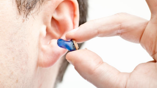 A close-up image of a modern hearing aid, small and discreet, blending in with the person's ear.