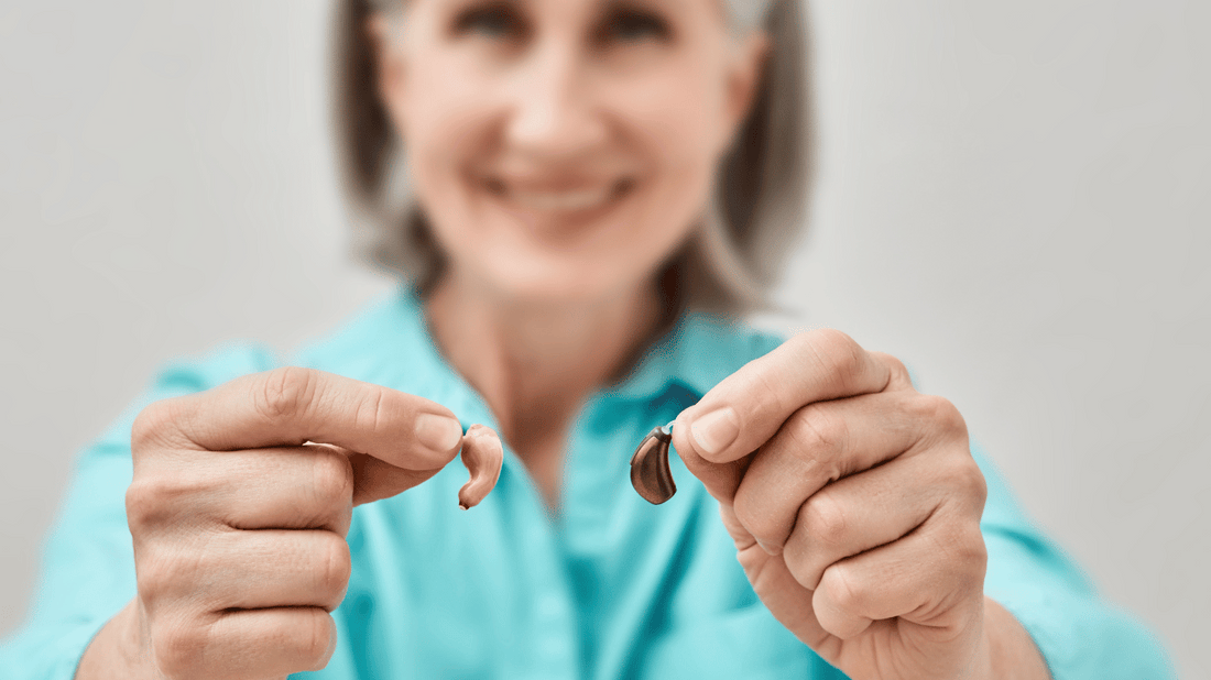 An image of a person holding over-the-counter hearing aids in their hand, representing purchasing hearing aids over-the-counter.