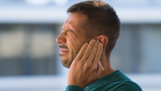 A person holding their ear with a pained expression, symbolizing tinnitus discomfort.