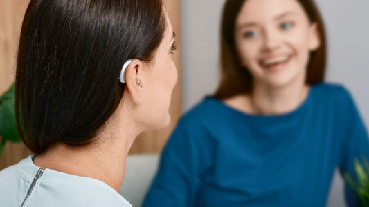 Person wearing rechargeable hearing aids, smiling and engaged in conversation.