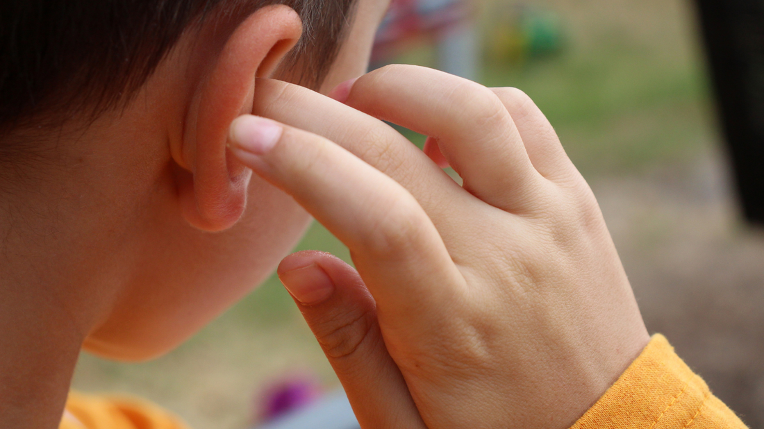 A person holding their hand to their ear with a concerned expression, symbolizing sudden hearing loss in one ear.