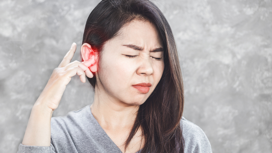 A person holding their ear in discomfort, symbolizing the experience of tinnitus with sound waves around their ear.