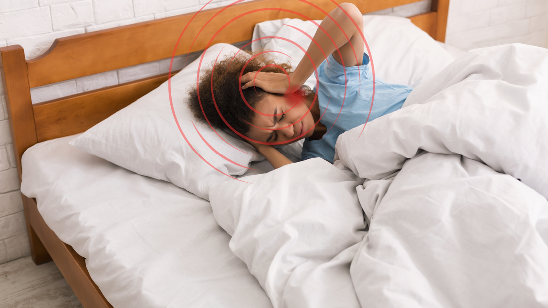 Illustration depicting a person lying in bed with their hand on their ear, looking disturbed, while invisible sound waves and symbols representing tinnitus swirl around their head