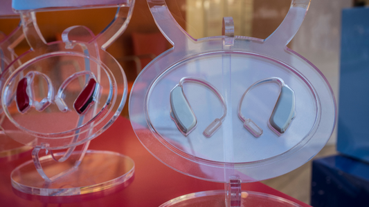 Two hearing aids displayed against a neutral background, symbolizing the importance of using two hearing aids for balanced hearing.