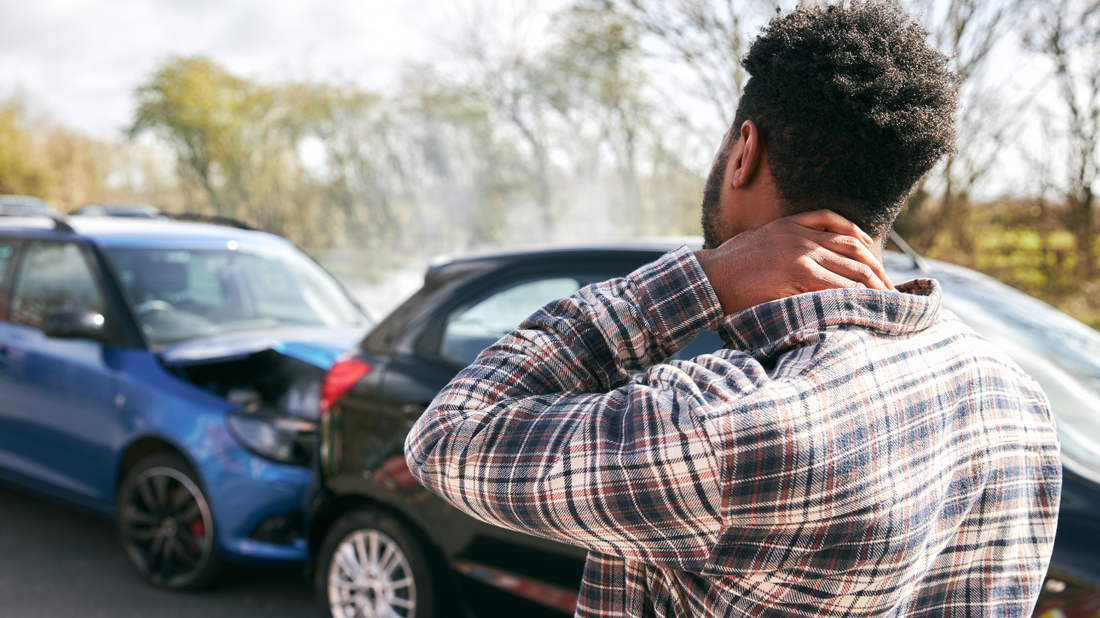 Image of a person holding their neck in pain after a car accident.